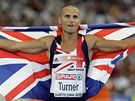 Brit Andy Turner s vlajkou slaví zlatou medaili ze závodu na 110 m pekáek.