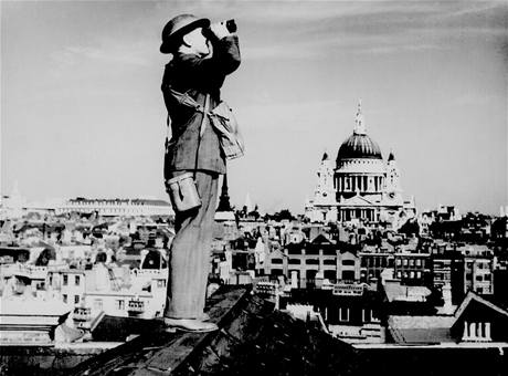 Britský voják vyhlíží německé bombardéry na střeše budovy v Londýně. V pozadí je vidět katedrála svatého Pavla. (září 1940)