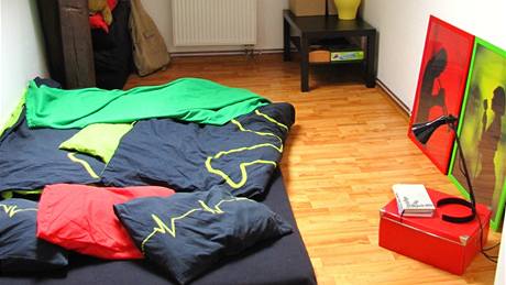 V malé lonici spí mladý pár na matraci. Noní stolky nahradily papírové krabice