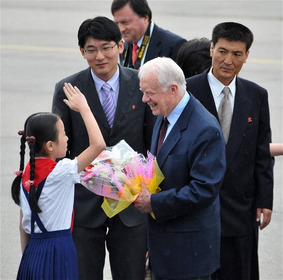 Jamese Cartera vítá na letiti v Pchjongjangu dívka s erveným átkem (25. srpna 2010) 