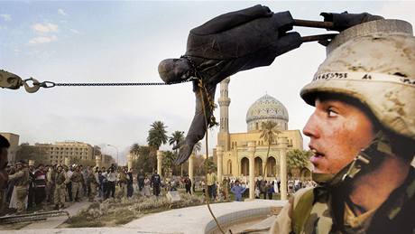 Americký voják sleduje strení Saddámovy sochy v iráckém Bagdádu. (9. dubna