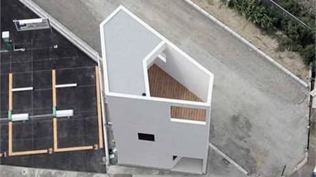 Minidm trojúhelníkového tvaru stojí mezi elezniní tratí a výkovým bytovým domem