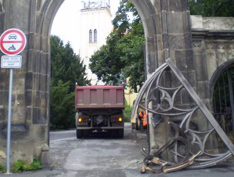 Nákladní auto s bagrem na korb urazilo kus historické brány.