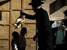 Ortodoxní id vykonává rituál kaparot nad hlavami dtí v jedné z jeruzalémských tvrtí (záí 2010)