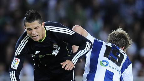 PADÁ HVZDA. Cristiano Ronaldo z Realu Madrid se ítí k zemi po zákroku Imanola Agirretxeho ze San Sebastianu.