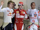 Fernando Alonso, vtz kvalifikace na Velkou cenu Singapuru (uprosted), pzuje fotografm s druhm Sebastianem Vettelem (vlevo) a tetm Lewisem Hamiltonem