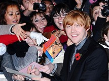 Pedstavitel Rona Rupert Grint se ped premirou Harryho Pottera podepisuje hlouku fanouk (Londn, 11. listopadu 2010)