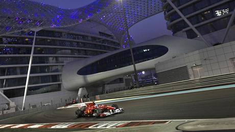 PED HOTELEM. Fernando Alonso z Ferrari projídí kolem moderního hotelu Yas Marina bhem kvalifikace Velké ceny Emirát.