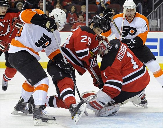 Branká New Jersey Devils Johan Hedberg se snaí lapakou pikrýt puk v zápase proti Philadelphii Flyers.