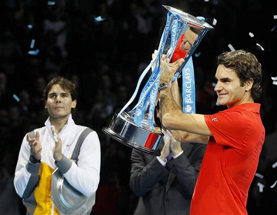 AMPION S TROFEJÍ. výcarský tenista Roger Federer pózuje s nablýskaným pohárem, opodál mu tleská i poraený finalista Rafael Nadal.
