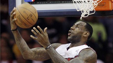 LeBron James (v bílém) z Miami Heat zakonuje pes atak Jamaria Moona z Clevelandu Cavaliers