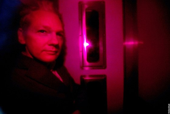 Julian Assange vyfocený skrze sklo policejního vozu při příjezdu k londýnskému soudu (14. prosince 2010)
