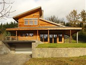 Fasády oblo�ené kamenem a mod�ínovým d�evem v p�írodní úprav� nenásiln� v�le�ují d�m do krajiny