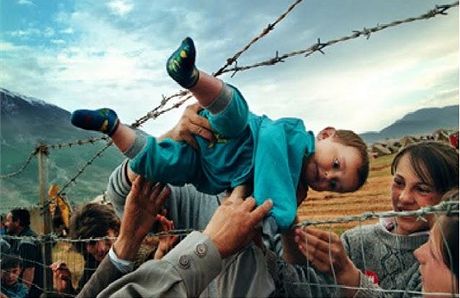 Shalovi, kteí utekli ped etnickými istkami z Kosova, podávají skrz ostnatý drát uprchlického tábora v Albánii prarodim dvouletého syna Akima. (3. kvtna 1999)