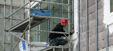 Martin Hrudek z firmy Hasil instaluje opláštění stěn u oken při výstavbě Centra technického vzdělávání v Ostrově. 