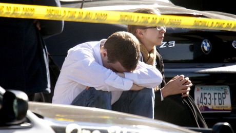 Zhroucení obyvatelé Tucsonu posedávají na místě, kde střelec spustil palbu (8. ledna 2010)