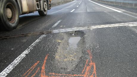 Díra na silnici I/13 mezi Komoany a Chomutovem, která zpsobila desítky