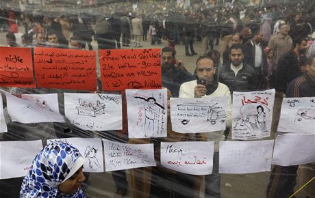 Demonstranti na khirskm nmst Tahrr si prohlej nstnku s protireimnmi slogany (8. nora 2011)