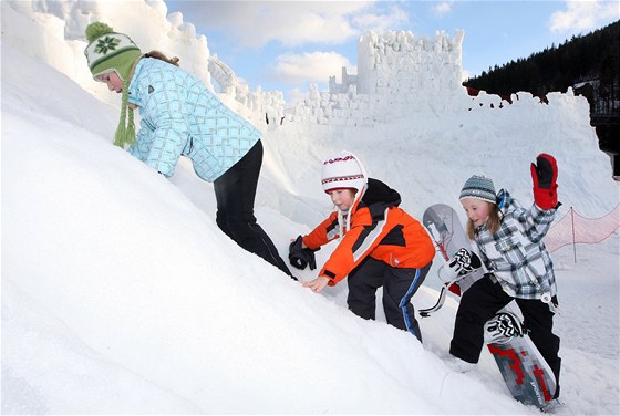 Děti si hrají u sněhového hradu Harrachštejn.