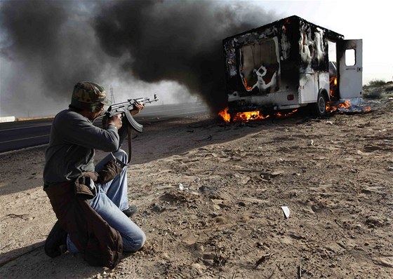 Libyjský povstalec míí na auto Kaddáfího jednotek poblí msta Brega (2. bezna 2011)