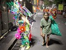 ena sbírající v ulicích brazilského Ria odpadky, prochází kolem jednoho z umlc pipravujících se na vystoupení ve slavném karnevalovém prvodu. (7. bezna 2011)
