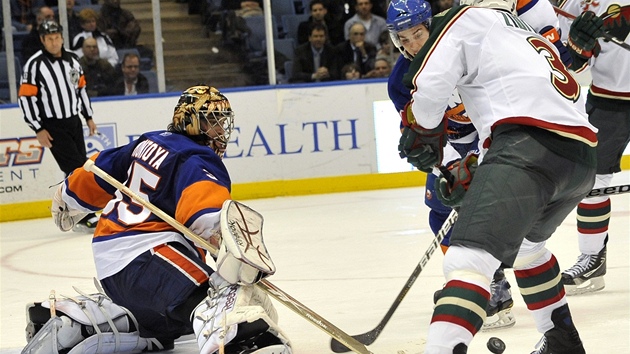 ZKÍENÉ HOLE. Obránce Marek idlický (. 3) z Minnesoty se snaí vypálit na gólmana Islanders Ala Montoyu, ale nic z toho nebylo, jen o sebe kísly jejich hokejky.