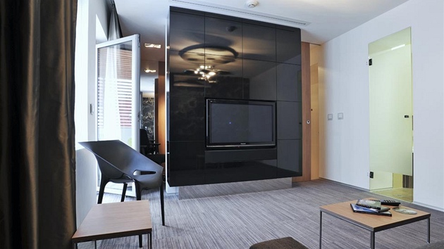 Panel uprost�ed místnosti rozd�luje byt na p�edsí�, hlavní obytný prostor a pracovnu. Jde o prostorovou uzav�enou knihovnu s vestav�ným televizorem a reproduktory, které jsou sou�ástí domácího kina.