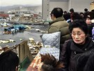 Lidé z japonské Kesennumy sledují spou napáchanou pívalovou vlnou tsunami. (11. bezna 2011)
