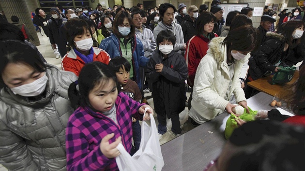 Evakuovaní Japonci si rozdlují jídlo v provizorním písteku ve Fukuim