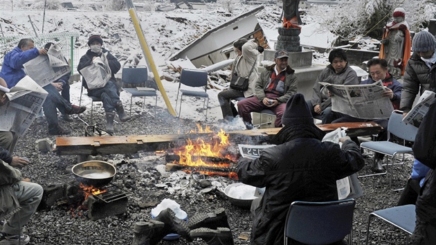 Lidé ze znieného japonského msta Otsui hledají v novinách erstvé informace o následcích tsunami.  (16. bezna 2011)