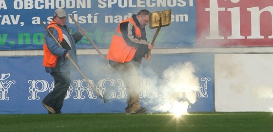 RYCHLE S TÍM PRY. Teplití poadatelé odklízejí dýmovnici, která vylétla ze sektoru fanouk Ostravy.