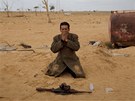 Povstalecký voják se modlí v libyjské pouti (21. bezna 2011)