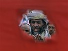 Jemenský demonstrant je vidt dírou ve vlajce (19. bezna 2011)