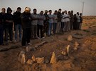 Libyjci postávají u erstvého hrobu neznámého lovka nedaleko Bregy na východ Libye (27. bezna 2011)