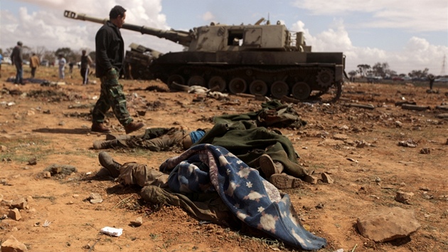 Libyjtí povstalci procházejí okolo tl Kaddáfího voják asi 35 kilometr západn od Benghází (20. bezen 2011)