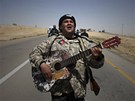 Hrdino, cos dlal za války? Libyjský rebel si vykrauje s kytarou  u msta Briga (5. dubna 2011)