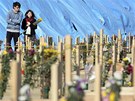 Mladý pár stojí u stovek rakví v Higaimatsuima v jedné z nejpostienjích prefektur Mijagi (4. dubna 2011)