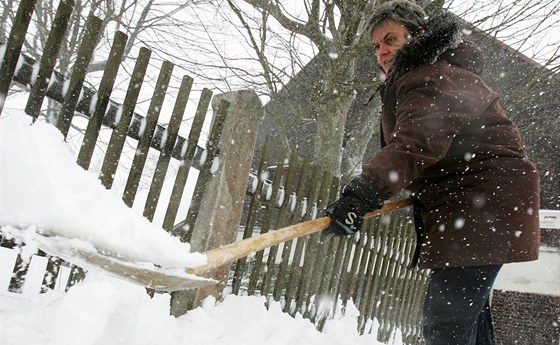 Do Kruných hor se vrátil sníh. Monika Rusnáková z Boího Daru uklízí sníh ped svým domem. (13.4. 2011)