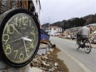 Mu na kole projídí kolem hodin zastavených ped msícem pi tsunami v japonském mst Miyako. (11. dubna 2011)