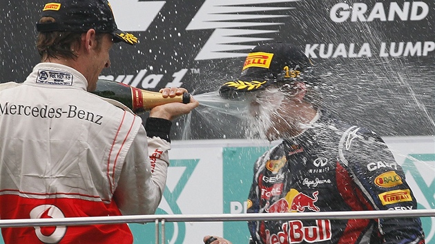 SPRCHA. Jenson Button kropí vítzného Sebastiana Vettela na stupních vítz po Velké cen Malajsie.