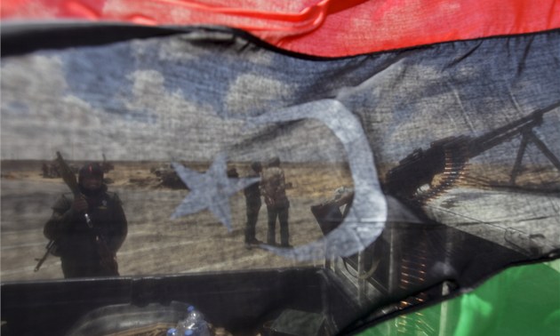 Rebelové jsou vid�t skrze bývalou libyjskou vlajku u m�sta Ad�edábíja (21. dubna 2011)
