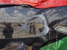 Rebelové jdou vidt skrze bývalou libyjskoun vlajku u msta Adedábíja (21. dubna 2011)