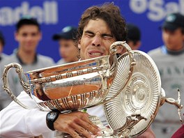 UNESU TO? Rafael Nadal se raduje s trofej pro vtze tenisovho turnaje v Barcelon.
