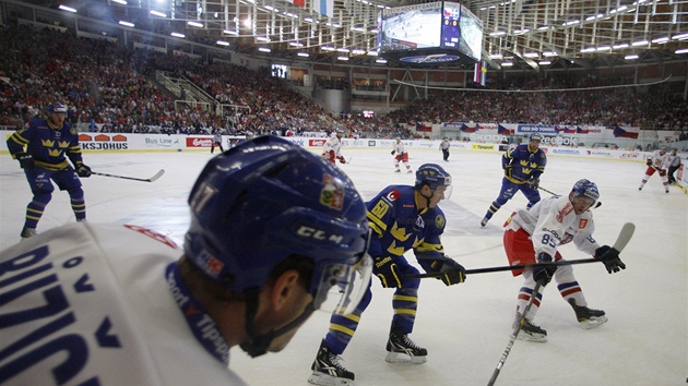 POHLED ZBLÍZKA. Martin Rika pihrává podél mantinelu Petru Vránovi, pihlíí véd Mikael Backlund.