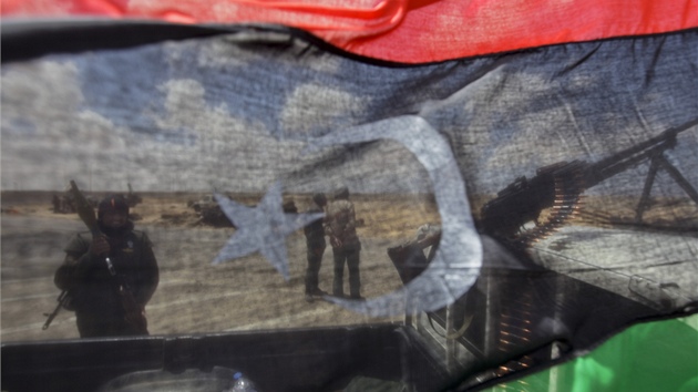 Rebelové jdou vidět skrze bývalou libyjskoun vlajku u města Adžedábíja (21. dubna 2011)