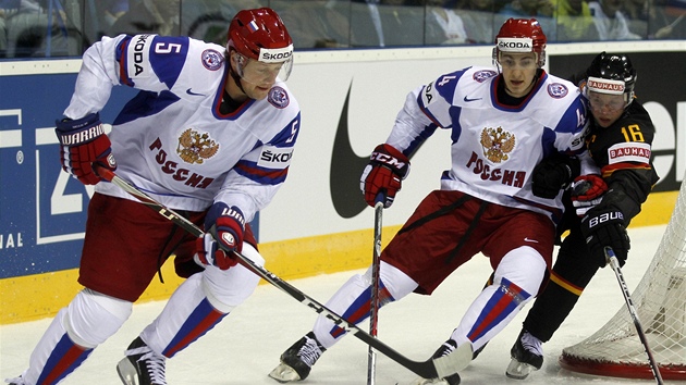 Ru�tí hokejisté Ilja Nikulin a Nikolaj B�lov u puku v utkání proti N�mecku, situaci se jim sna�í zkomplikovat Michael Wolf. 