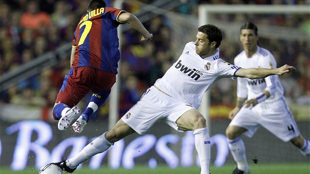 DLOUHÁ NOHA. Xabi Alonso z Realu Madrid (v bílém) ist zastavuje pronikajícího Davida Villu z Barcelony.