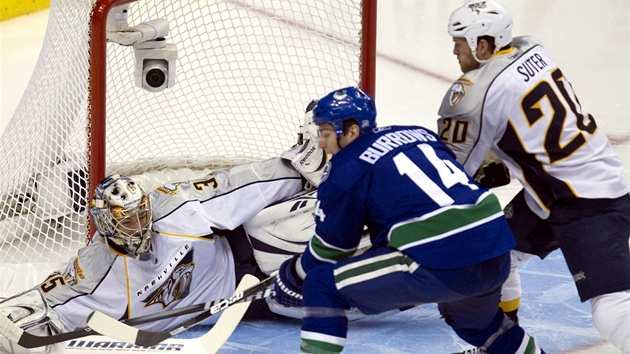 Vancouverský Alex Burrows (v modrém) v anci ped gólmanem  Pekkou Rinnem z Nashvillu. 