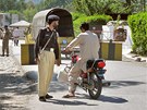 Pakistánský policista provuje motocyklistu na kontrolním stanoviti ve mst...