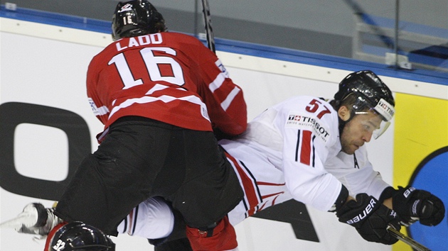 Andrew Ladd, z Kanady tla�í na mantinel �výcara Gorana Bezinu.